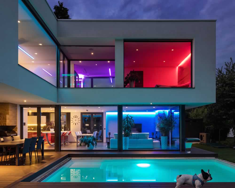 modern home with pool lit up at night with colourful electrical LED lighting